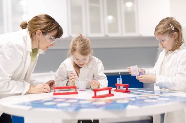 Genç öğrenci okulda öğretmeninin yardımıyla laboratuvarda çalışıyor.