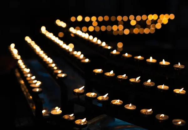 stock image Tealight candles arranged in row in dark church