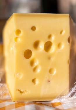 Piece of delicious emental cheese with holes clipart