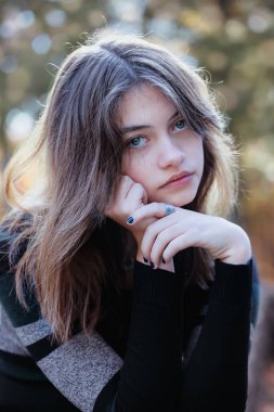 Güzel esmer, genç bir kadın ne yazık ki sonbahar renkleriyle çevrili kameraya bakıyor. Bulanık arkaplan ile seçmeli odak.