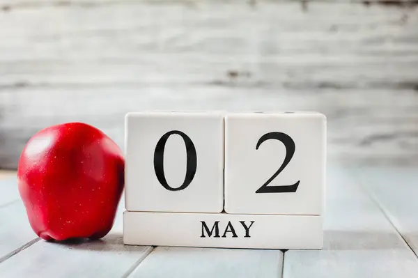 ホワイトウッドのカレンダーブロックは5月2日と国家教師の感謝の日の赤いリンゴです ロイヤリティフリーのストック画像