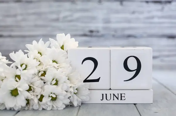 ホワイトウッドのカレンダーブロックは 6月29日とホワイトデイジーの日付です バックグラウンドで選択的なフォーカス ストック画像