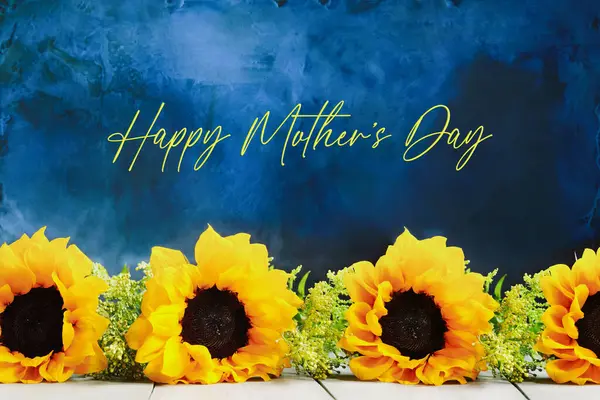 母亲节那天 一排排美丽的向日葵 衬托着蓝色的和平背景 并附有文字 前面的景色背景模糊的选择性重点 图库图片