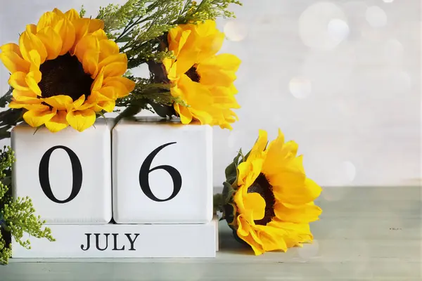 事実上仮想アシスタントデーをハグする ホワイトウッドのカレンダーブロックは 7月6日とボケの美しい日光花の花束で バックグラウンドで選択的なフォーカス ロイヤリティフリーのストック画像