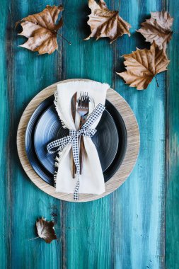 Şükran Günü için arka planda tabaklar, peçeteler ve gümüşlerle süslenmiş ve kurumuş yapraklarla süslenmiş bir sonbahar tatili yeri. Düz yatay veya tepe noktasından en üstteki görüntüyü al. 