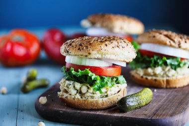 Vejetaryen vejetaryen sandviçi, nohut ezmesi, marul, taze domates dilimleri ve yanında turşulu soğan her şeyin üzerine taze çörek. Bulanık arkaplan ile seçmeli odak.