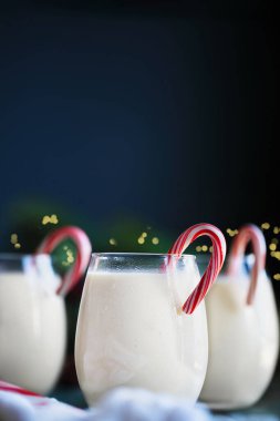 Dikey olarak kremalı eggnog ve baston şeker. Bulanık şenlik arkaplanlı seçici odak.