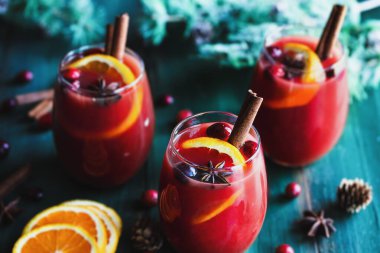 Üç bardak Noel şarabı, portakal dilimli kırmızı şarap, tarçın kabuğu, anason ve firavun ağacı dalları rengarenk masa üzerinde. Önplanı ve arkaplanı bulanık seçili odak.