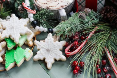 Buzlu Noel kar tanesi ve ağaç şekilli kurabiyeler ya da kırsal bir masada yeşil kremalı bisküviler. Bulanık arkaplan ile seçmeli odak.