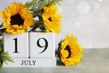  Ulusal Futbol Günü. 19 Temmuz tarihli beyaz tahta takvim blokları ve Bokeh 'li güzel ayçiçeği buketi. Bulanık arkaplan ile seçmeli odak. 