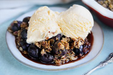 Fransız vanilyalı dondurmayla servis edilen ev yapımı kirazlı gevrek. Bulanık arkaplan ile seçmeli odak.