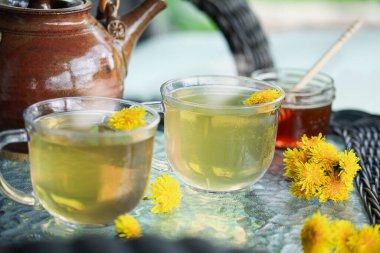 Bitkisel ilaçlar için içi canlı karahindiba çayıyla dolu dumanı tüten iki sıcak fincan. Bulanık arkaplan ile seçmeli odak,