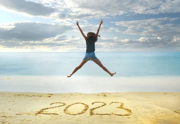 2023年新年写在沙滩上 快乐的女孩手举着手在海滩上跳跃 — 图库照片#