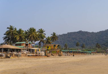 Agonda plaj renkli kulübelerde palm ağaçlar arka plan Goa, Hindistan.