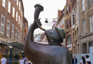 Bremen, Almanya 'da işlek bir yaya caddesinde korna çalan bir adamın bronz heykeli. Heykel tarihi binaların arasında duruyor ve şehrin kültürel atmosferini yansıtıyor..