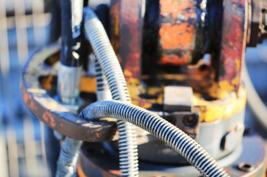 Endüstriyel hidrolik hortumların ve paslanmış metal bileşenlerin yakın görüntüsü. İnşaat, makine bakımı ve ağır ekipman sistemlerinde kullanılan esnek borular ve mekanik tesisatlara odaklan