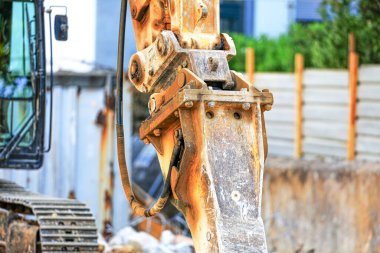 Hidrolik çekiç takılı kazıcı kolu görüntüsü. Yıpranmış metal, civata ve hortumlar, aktif bir kentsel iş sahasında ağır kullanım olduğunu ortaya koyuyor.