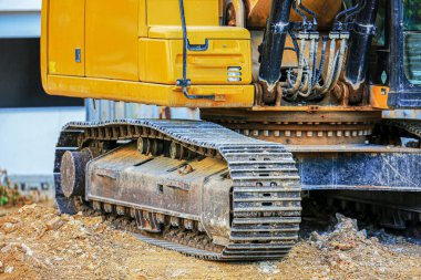 Bir inşaat alanındaki kazıcıların çelik pist ve dönüşümlü üslerini kapatın. Endüstriyel veya kentsel kalkınma projelerinde engebeli arazi ve toprak taşınımı için tasarlanmış ağır iş makineleri