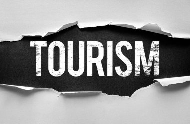 Grunge tarzı kelime TOURISM yırtık kağıdın altında ortaya çıktı. Seyahat, keşif ve keşfi temsil eden kavramsal bir görüntü. Kalın tipografili yüksek karşıtlık tasarımı