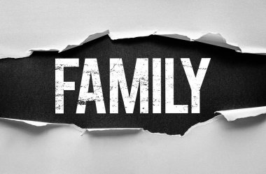 Kelime AİLESİ kalın desenli yazı tipi ile yırtık bir kağıt arka planda görünür. İlişkileri, desteği, evi, sevgiyi, bağlantıyı veya aile değerlerini ve duygusal bağları temsil eden kavramsal görüntü