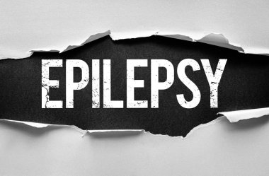 Epilepsi metni yırtık kağıdın arkasındaki sıkıntılı ve kalın yazı tipi, nöbetlerle ve nörolojik durumlarla gizli mücadeleyi, farkındalığı, eğitimi ve etkilenen bireylere destek vermeyi simgeler.