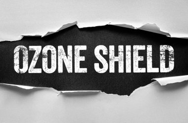 OZON SHIELD metni yırtık kağıtlar aracılığıyla ortaya çıkar, atmosfer korumasını, çevresel korumayı, ultraviyole savunmayı ve gezegenlerin sağlığını korumanın önemini simgeler.