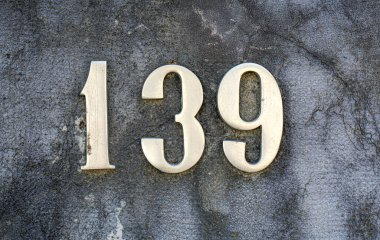 139 numaralı ev metalik şekilli yıpranmış beton duvara monte edilmiş. Klasik gümüş rakamlar desenli detaylar, mülkiyet tanımlaması konsepti, sokak adresi işareti ve mimari öğesi