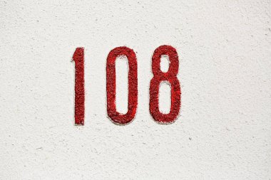 108 numaralı ev beyaz bir duvarda kırmızı dokuya boyanmış. Kaba bitiş ile kalın sayısal işaret, mülkiyet tanımlama konsepti, sokak adresi işaretleme ve mimari detay