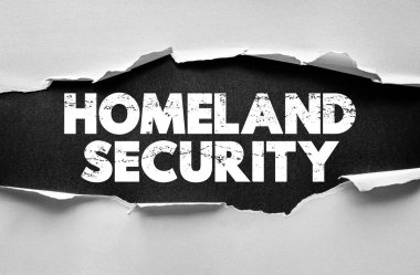 HOMELAND GÜVENLİK Yırtık kağıt üzerinde kalın bir metin. Ulusal savunma, güvenlik, yasa uygulama, sınır denetimi ve kamu risk yönetimini vurgulayan hükümet koruma kavramı