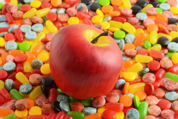 苹果堆在各种糖果的背景上 — 图库照片