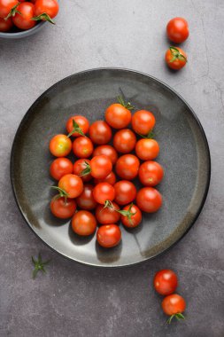 Gri tabakta taze vişneli domatesler
