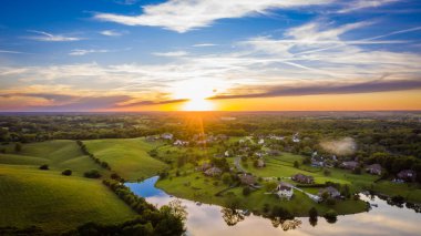 Scenic aerial view of sunset over rural neighborhood and a lake in Central Kentucky clipart