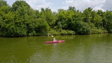 Kamera Kentucky 'de küçük bir gölde kano süren bir kadını takip ediyor.