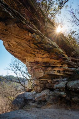 Sun peaking from behind Double Arch rock formation in Red River Gorge geological area in Kentucky clipart