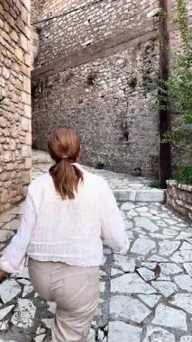 Kamera, Yunanistan 'ın Arcadia bölgesindeki bir köyün caddesinde yürüyen bir kadını izliyor