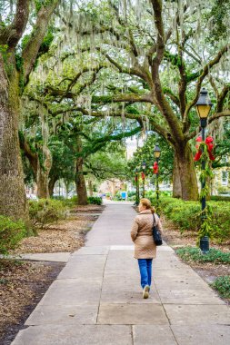 Bir kadın Savannah, Georgia 'daki Forsyth Park' ın manzaralı bir sokağında yürüyor.