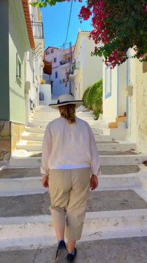 Yunanistan 'ın Mora eyaletinin Koroni kasabasında bir yayanın merdivenlerinde yürüyen bir kadının dikey video klibi