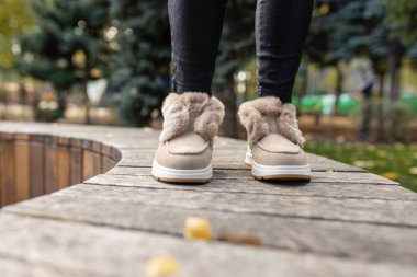 Gri kaldırım taşlarında yumuşak tüyleri ve yapay elmasları olan şık bej sonbahar kış kış ayakkabıları