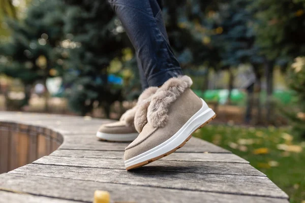 时尚时髦的米黄色秋冬鞋 灰色铺路石上有柔软的浅色毛皮和莱茵石 — 图库照片