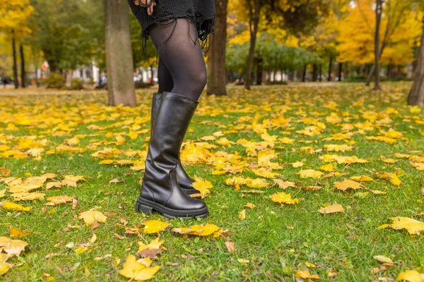 一个穿着保暖靴的女孩在落叶的背景下摆姿势 — 图库照片