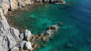 Dalgaların mavi okyanustaki Alanya Hindi kıyısındaki kayalıklardaki uçurumlara düşüşünü gösteren hava manzarası. Yeşil doğa ve okyanusun hava aracı fotoğrafçılığı