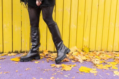 Sıcacık çizmeli bir kız arka planda düşen yapraklara poz veriyor.. 