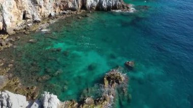 Dalgaların mavi okyanustaki Alanya Hindi kıyısındaki kayalıklardaki uçurumlara düşüşünü gösteren hava manzarası. Yeşil doğa ve okyanusun hava aracı fotoğrafçılığı