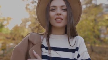 Kahverengi şapkalı güzel bir sarhoşun yakın çekimi, parkta yürüyüş, kameraya poz vermek. Sonbaharda parkta yürüyen zarif beyaz bir bayanın moda portresi.. 