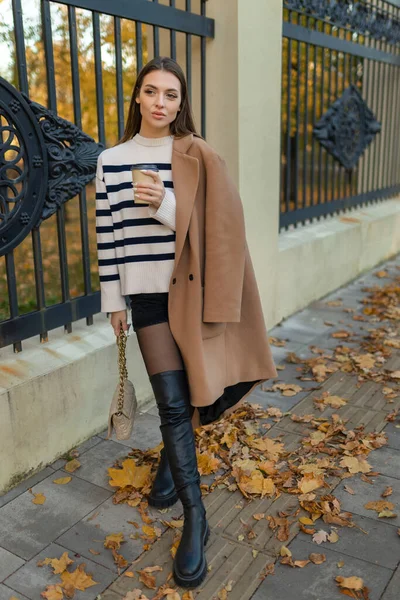 穿着格子外套 太阳镜 心情愉快 时尚潮流的迷人的年轻女子穿着咖啡在秋天的公园散步 — 图库照片