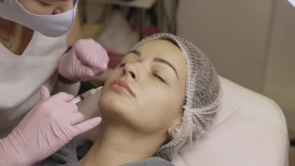 美容クリニックでの手続きの美しい女性 充填注射だ紫色の手袋の医師は 鼻腔内の折り目に注射を行います — ストック動画