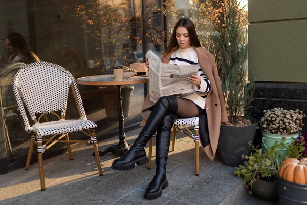 코트를 아름다운 카페에서 쉬면서 신문을 미소를 짓는다 — 스톡 사진