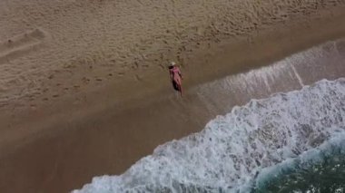 Deniz kenarında uzanmış deniz dalgalarının tadını çıkaran pembe bikinili genç, şehvetli sarışın bir kadının üst görüntüsü. Tatillerin ve hafta sonları kaçamakların hayalini kuruyorum.