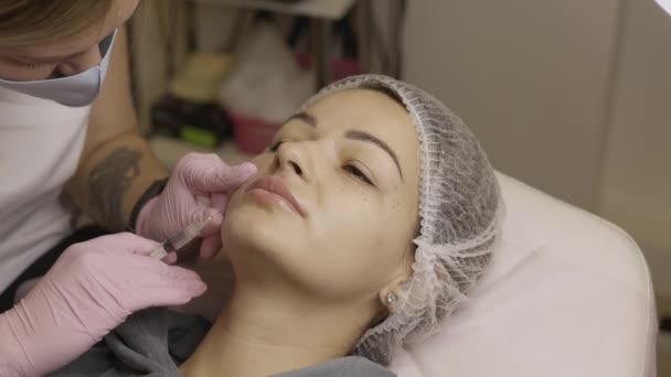 美容クリニックでの手続きの美しい女性 充填注射だ紫色の手袋の医師は 鼻腔内の折り目に注射を行います — ストック動画