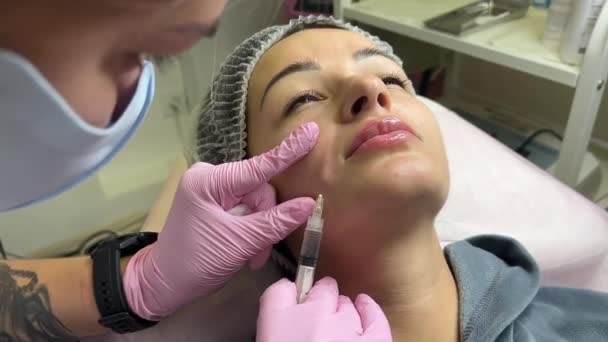 美容院正在做手术的美女 填充注射剂 戴紫色手套的医生在鼻唇褶皱处注射 — 图库视频影像